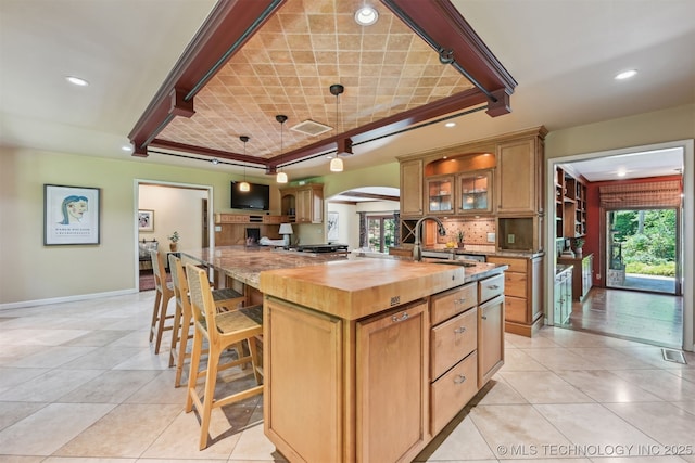 3898 E 72nd St, Tulsa, OK 74136 - kitchen featuring butcher block counters, arched walkways, baseboards, tasteful backsplash, and light tile patterned floors