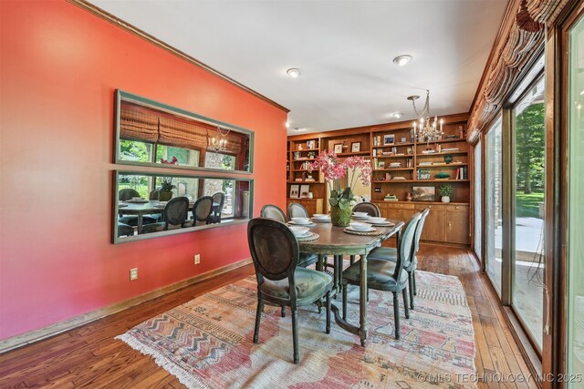 3898 E 72nd St, Tulsa, OK 74136 - dining room with a chandelier, wood-type flooring, crown molding, built in features, and baseboards