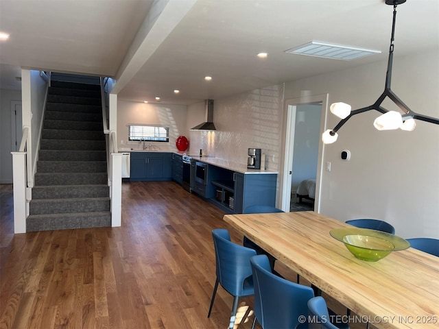 56648 Bloomer Rd, Afton, OK 74331 - kitchen with wall chimney range hood, a sink, dark wood finished floors, light countertops, and blue cabinets