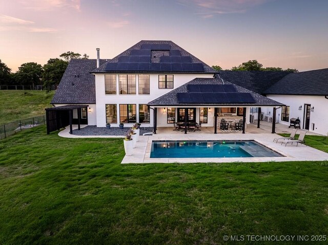 589 Three Mile Rd, Durant, OK 74701 - back of house at dusk with roof with shingles, roof mounted solar panels, a patio area, outdoor dining space, and an outdoor hangout area