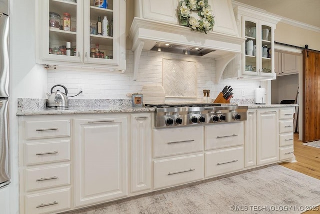 589 Three Mile Rd, Durant, OK 74701 - kitchen with stainless steel gas cooktop, backsplash, a barn door, light wood finished floors, and glass insert cabinets