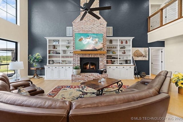 589 Three Mile Rd, Durant, OK 74701 - living room featuring a towering ceiling, ceiling fan, light wood-style flooring, healthy amount of natural light, and a brick fireplace