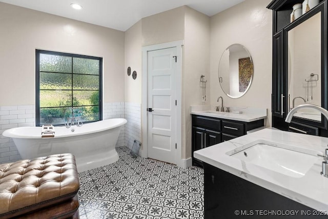 589 Three Mile Rd, Durant, OK 74701 - bathroom featuring tile walls, two vanities, a freestanding tub, a wainscoted wall, and recessed lighting