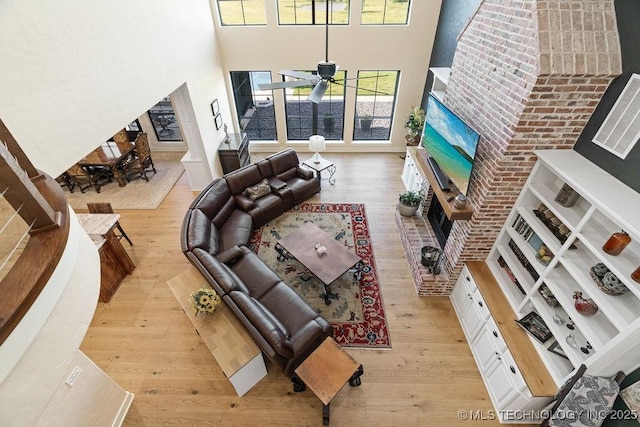 589 Three Mile Rd, Durant, OK 74701 - living room featuring a towering ceiling, wood finished floors, a fireplace, and a ceiling fan