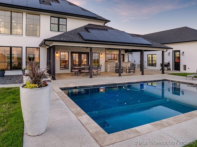589 Three Mile Rd, Durant, OK 74701 - back of property featuring a patio, french doors, roof mounted solar panels, an outdoor pool, and a shingled roof