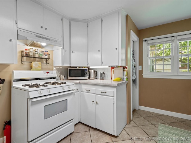 1626 S Dewey Ave, Bartlesville, OK 74003 - kitchen with gas range gas stove, stainless steel microwave, under cabinet range hood, light countertops, and light tile patterned flooring