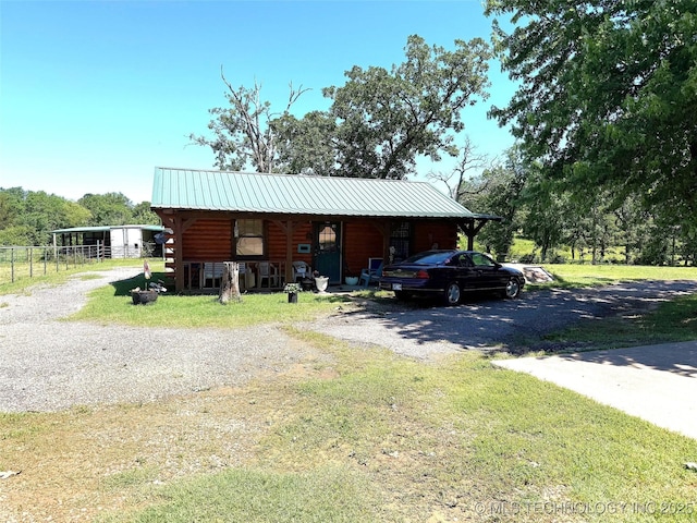 7905 Hornbeam Rd, Henryetta, OK 74437 - view of front of house with gravel driveway, metal roof, and log siding