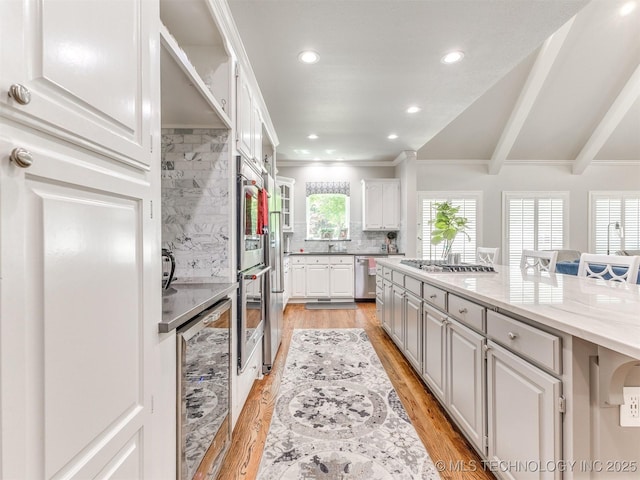 609 E Pensacola St, Broken Arrow, OK 74011 - kitchen featuring beverage cooler, white cabinetry, backsplash, light wood-type flooring, and light stone countertops