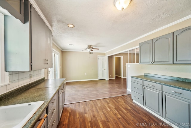 8009 E 2nd St, Tulsa, OK 74112 - kitchen with dark wood-style floors, a textured ceiling, crown molding, a ceiling fan, and dark countertops