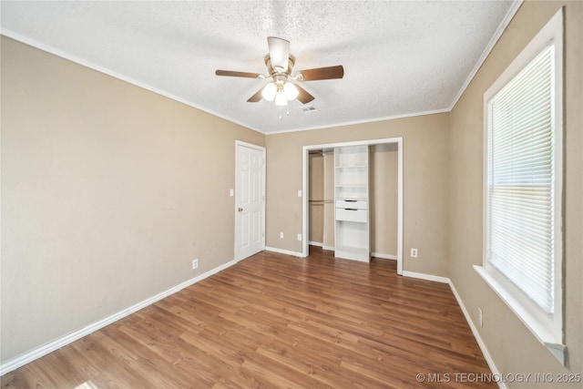 8009 E 2nd St, Tulsa, OK 74112 - unfurnished bedroom featuring a textured ceiling, wood finished floors, ornamental molding, baseboards, and a closet