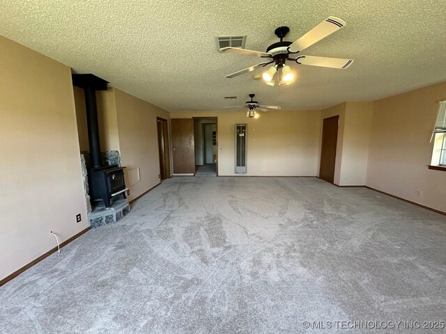 109948 S 4155th Rd, Checotah, OK 74426 - unfurnished living room with a ceiling fan, baseboards, a textured ceiling, carpet, and a wood stove