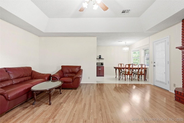 12013 E 27th St, Tulsa, OK 74129 - living room with light wood-type flooring, ceiling fan, a tray ceiling, and baseboards