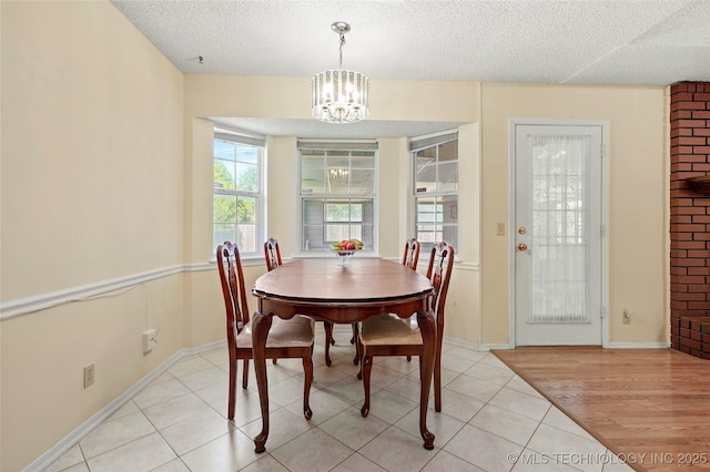12013 E 27th St, Tulsa, OK 74129 - dining space with a textured ceiling, a chandelier, light tile patterned floors, and baseboards