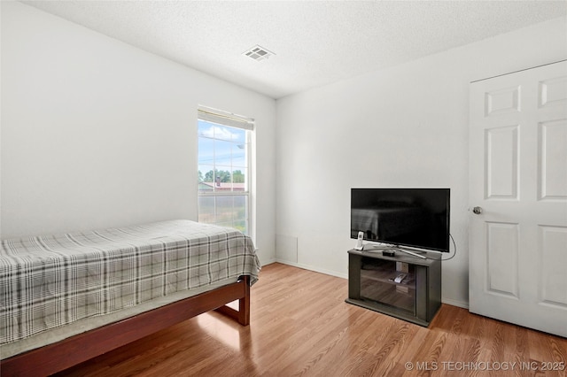 12013 E 27th St, Tulsa, OK 74129 - bedroom with wood finished floors, baseboards, and a textured ceiling