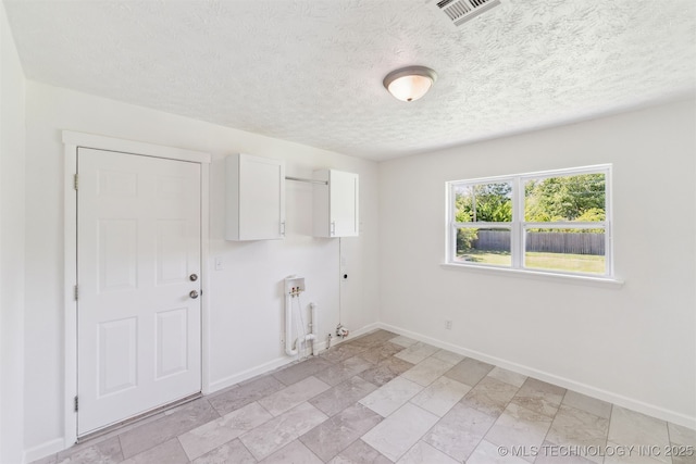 201 W 9th St, Claremore, OK 74017 - laundry area with cabinet space, gas dryer hookup, baseboards, and a textured ceiling