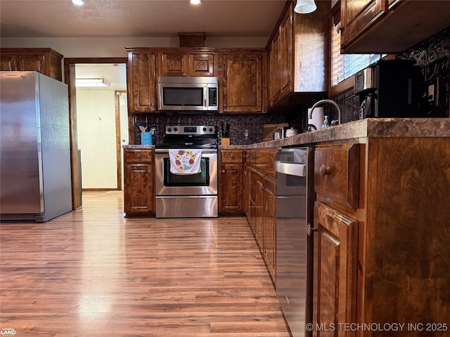 1965 Mcalester Lk, Mcalester, OK 74501 - kitchen featuring appliances with stainless steel finishes, light wood finished floors, decorative backsplash, and a sink