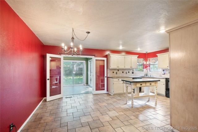 10511 S 83rd Cir, Tulsa, OK 74133 - kitchen with a chandelier, baseboards, backsplash, hanging light fixtures, and white cabinetry