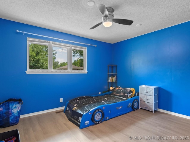 2318 Dorchester Dr, Bartlesville, OK 74006 - bedroom with wood finished floors, a textured ceiling, baseboards, and a ceiling fan