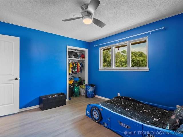2318 Dorchester Dr, Bartlesville, OK 74006 - bedroom with wood finished floors, a textured ceiling, a closet, ceiling fan, and baseboards