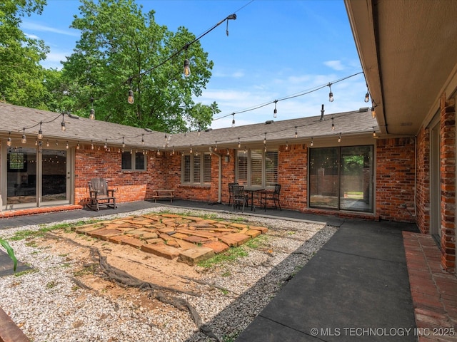 2318 Dorchester Dr, Bartlesville, OK 74006 - rear view of property featuring a patio area, brick siding, and a shingled roof