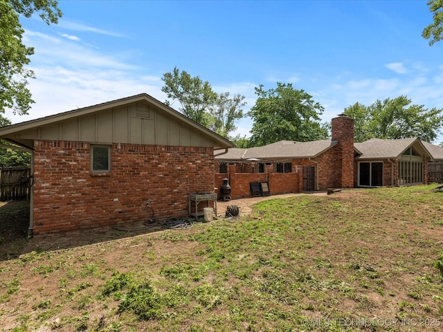 2318 Dorchester Dr, Bartlesville, OK 74006 - back of house with a chimney, brick siding, and board and batten siding