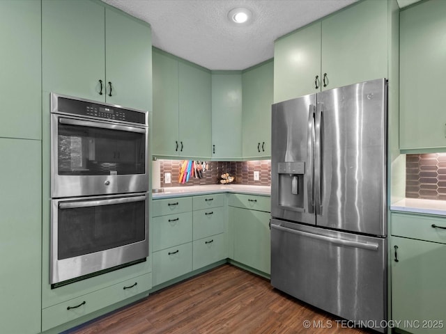 2318 Dorchester Dr, Bartlesville, OK 74006 - kitchen with appliances with stainless steel finishes, green cabinetry, light countertops, dark wood-style flooring, and a textured ceiling