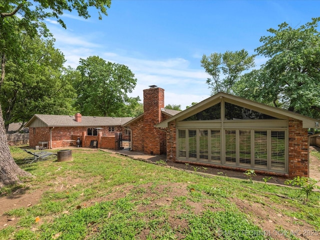 2318 Dorchester Dr, Bartlesville, OK 74006 - rear view of property with brick siding, a chimney, and a yard