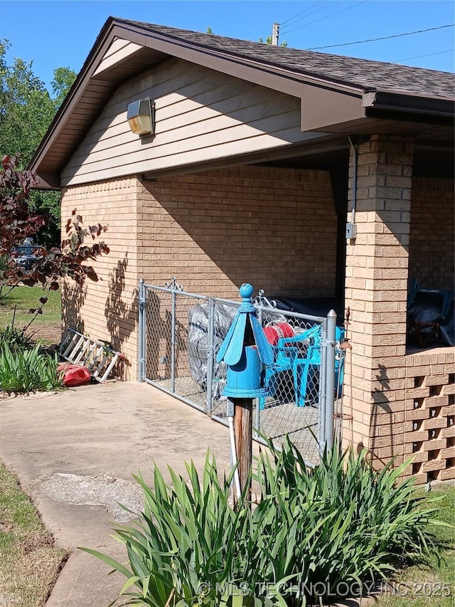 715 Kiowa, Hartshorne, OK 74547 - view of side of home with brick siding, a patio, and a gate