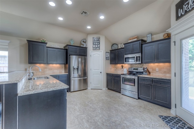 10216 N 120th E Ave, Owasso, OK 74055 - kitchen with appliances with stainless steel finishes, a sink, light stone counters, a peninsula, and vaulted ceiling