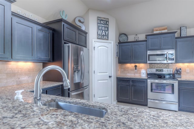 10216 N 120th E Ave, Owasso, OK 74055 - kitchen featuring appliances with stainless steel finishes, lofted ceiling, light stone counters, backsplash, and a sink