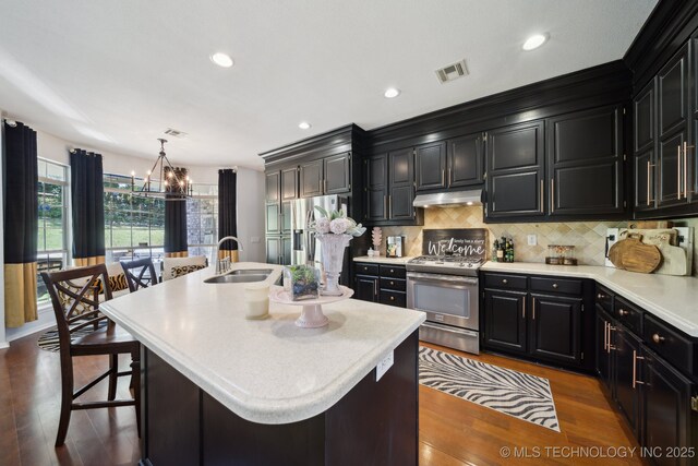 4602 S Linwood Dr, Sand Springs, OK 74063 - kitchen featuring appliances with stainless steel finishes, dark cabinets, a chandelier, under cabinet range hood, and recessed lighting