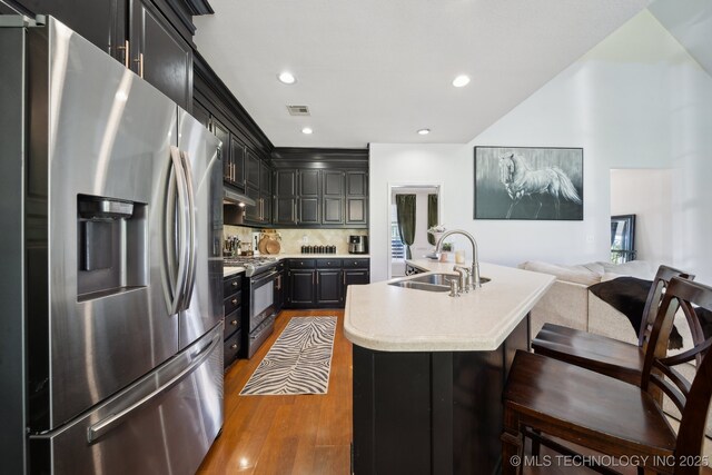 4602 S Linwood Dr, Sand Springs, OK 74063 - kitchen featuring stainless steel appliances, light countertops, wood finished floors, a kitchen island with sink, and dark cabinetry