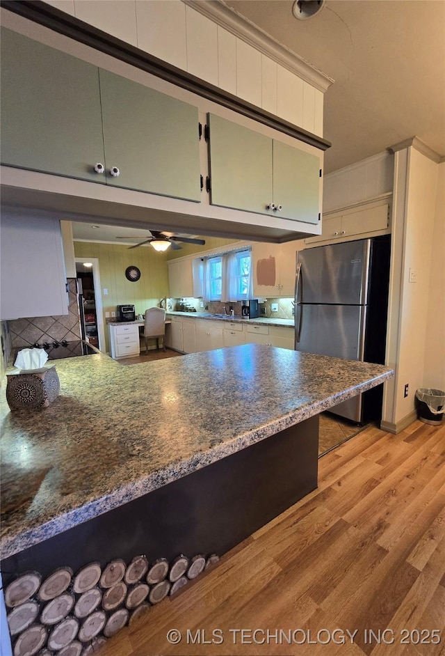 1324 N 3rd, Durant, OK 74701 - kitchen with freestanding refrigerator, light wood-type flooring, a peninsula, decorative backsplash, and a ceiling fan