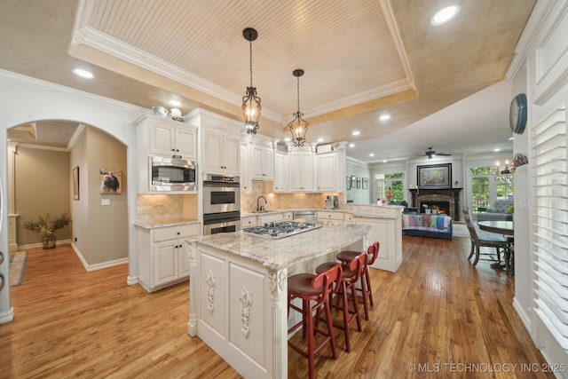 3335 E 93rd St, Tulsa, OK 74137 - kitchen with a tray ceiling, stainless steel appliances, a peninsula, a center island, and light wood-type flooring