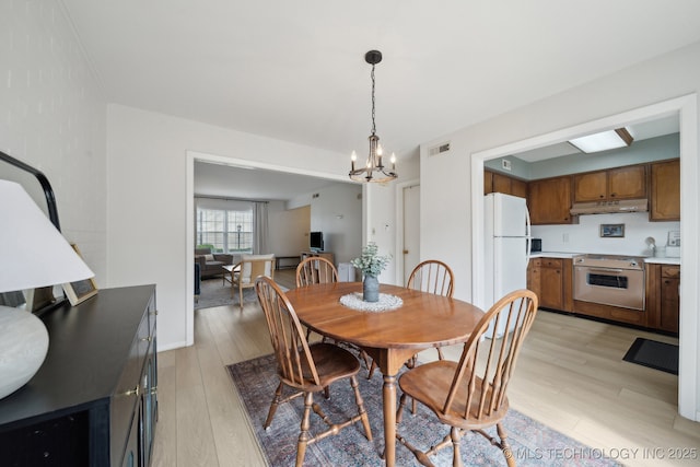5538 E 46th St Unit 9, Tulsa, OK 74135 - dining area featuring light wood-style floors and a chandelier