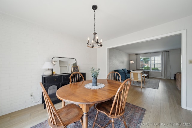5538 E 46th St Unit 9, Tulsa, OK 74135 - dining area featuring brick wall, a chandelier, and light wood-type flooring