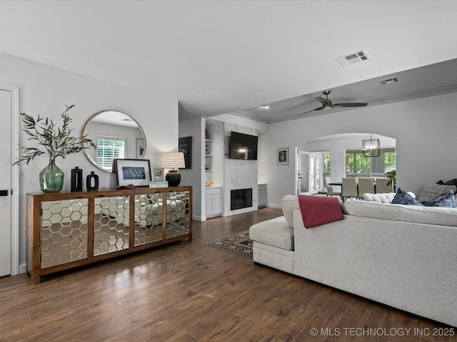 5553 S Delaware Ct, Tulsa, OK 74105 - living room featuring wood finished floors, a fireplace, plenty of natural light, and arched walkways