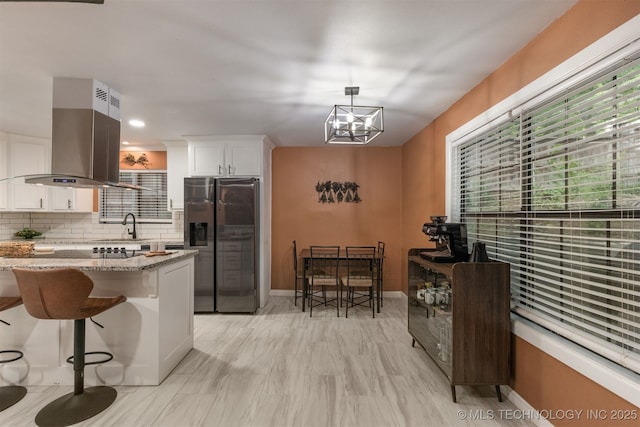 7423 S Urbana Ave, Tulsa, OK 74136 - kitchen with stainless steel fridge, island exhaust hood, backsplash, light stone countertops, and a chandelier