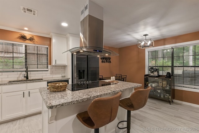 7423 S Urbana Ave, Tulsa, OK 74136 - kitchen featuring island range hood, a sink, black electric stovetop, light stone countertops, and backsplash