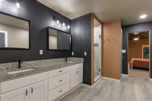 7423 S Urbana Ave, Tulsa, OK 74136 - ensuite bathroom with wood finished floors, a textured wall, double vanity, a shower stall, and baseboards