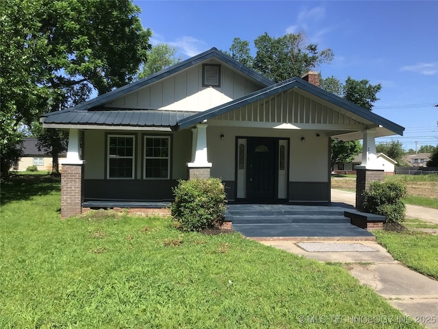 218 N Vann St, Pryor, OK 74361 - view of front of property with board and batten siding, covered porch, a front lawn, and a chimney