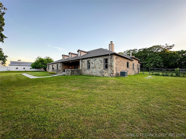 16012 N 145th Ave, Collinsville, OK 74021 - rear view of house featuring a chimney, stone siding, and central air condition unit
