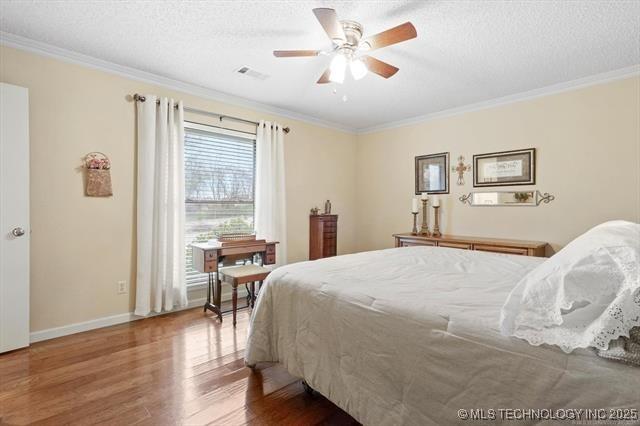 20941 E 102nd St S, Broken Arrow, OK 74014 - bedroom with wood finished floors, ornamental molding, a textured ceiling, baseboards, and ceiling fan