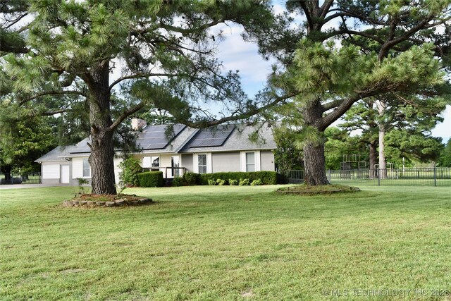 74232 S 320th Rd, Wagoner, OK 74467 - view of front of home with roof mounted solar panels, a garage, and a chimney