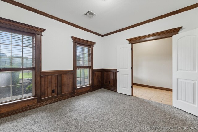 7083 E 85th St N, Owasso, OK 74055 - spare room featuring light colored carpet, healthy amount of natural light, a wainscoted wall, ornamental molding, and light tile patterned floors