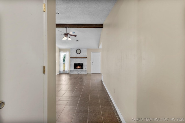 hall featuring dark tile patterned flooring, a textured ceiling, and baseboards