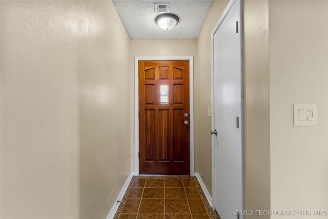 entryway with baseboards, a textured ceiling, and dark tile patterned floors