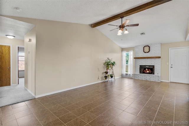 unfurnished living room with a ceiling fan, dark tile patterned floors, a fireplace, a textured ceiling, and baseboards
