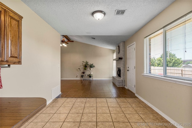 unfurnished living room featuring light tile patterned floors, vaulted ceiling, a fireplace, a textured ceiling, and a ceiling fan