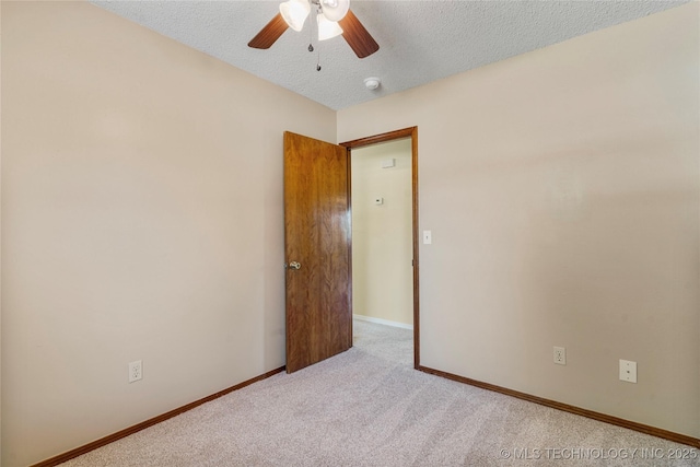 carpeted empty room with a textured ceiling, a ceiling fan, baseboards, and a smoke detector